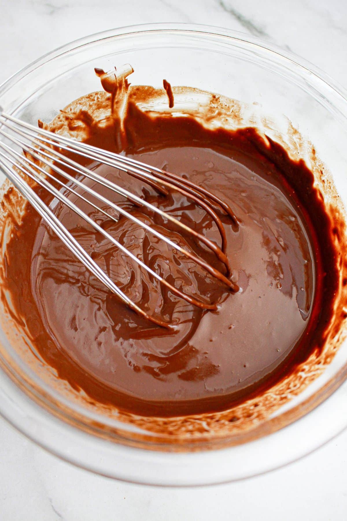 cupcake batter being mixed with a whisk in a glass mixing.