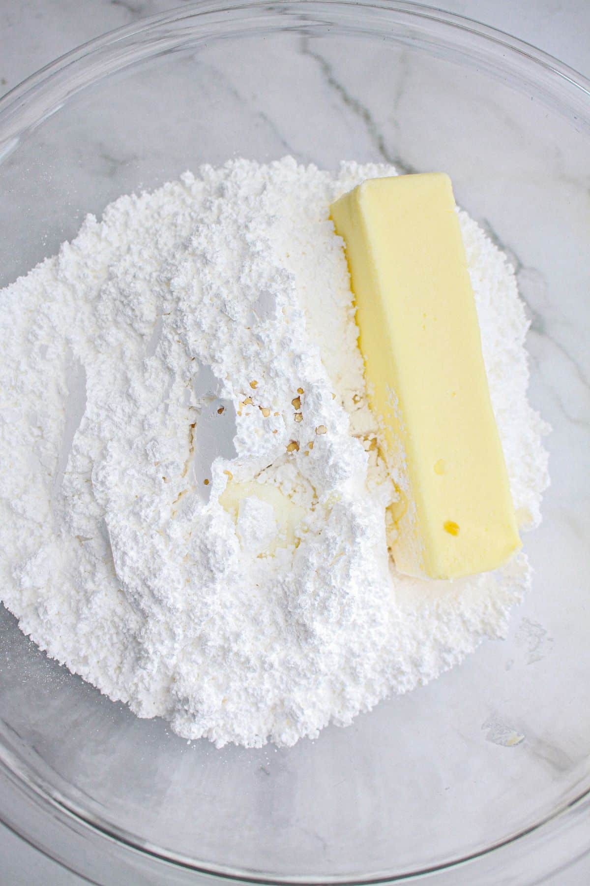 powdered sugar, butter, and heavy cream in a glass mixing bowl.