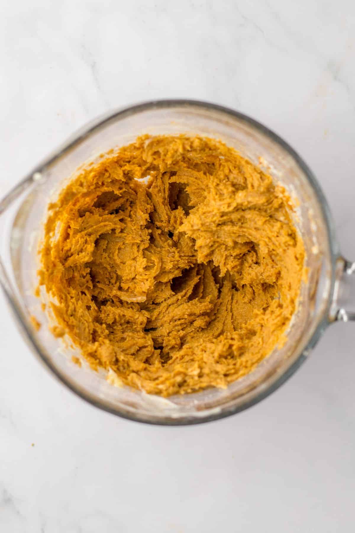 butter, brown sugar, and and vanilla being mixed to make a cinnamon sugar filling a glass bowl.