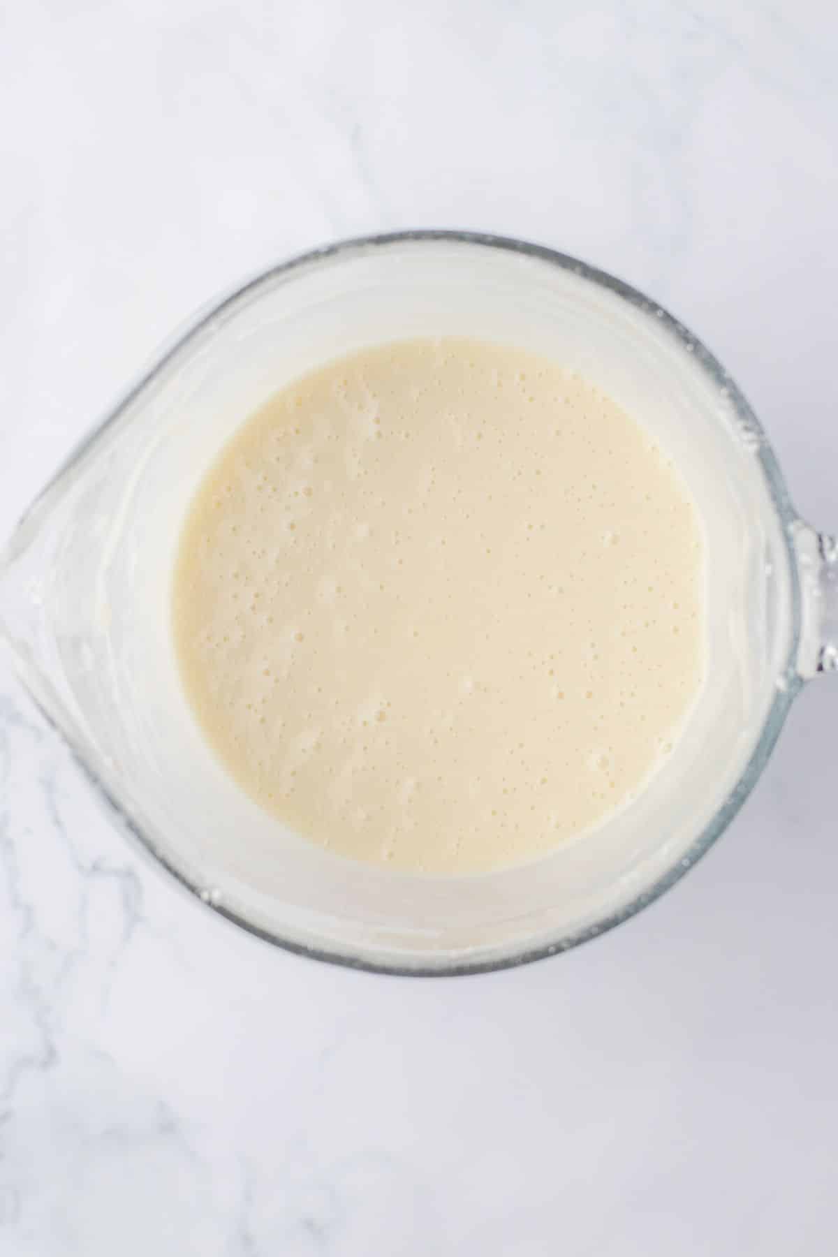 vanilla glaze being mixed in a glass mixing bowl.