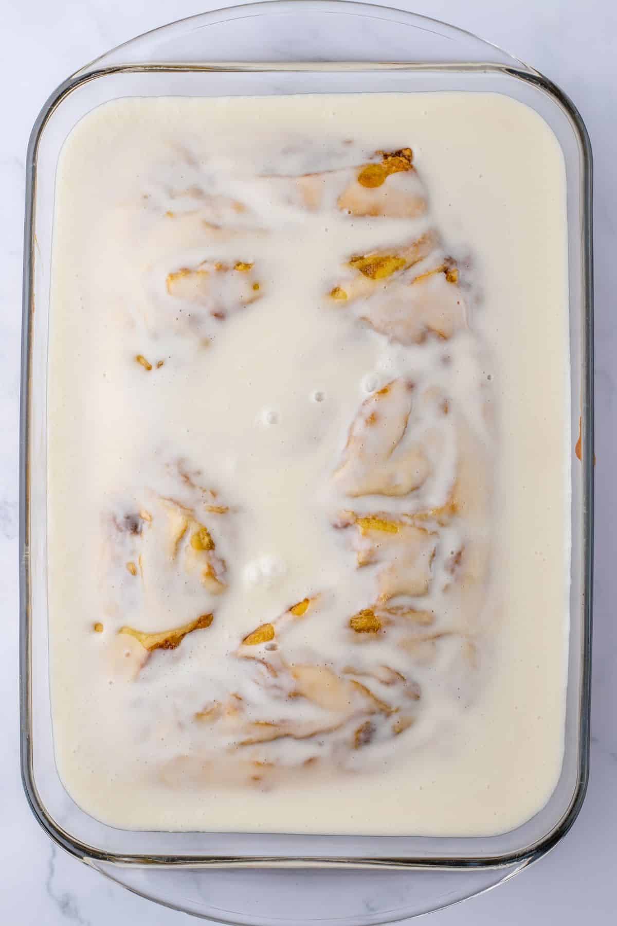 glaze being poured on top of a cinnamon swirl cake.
