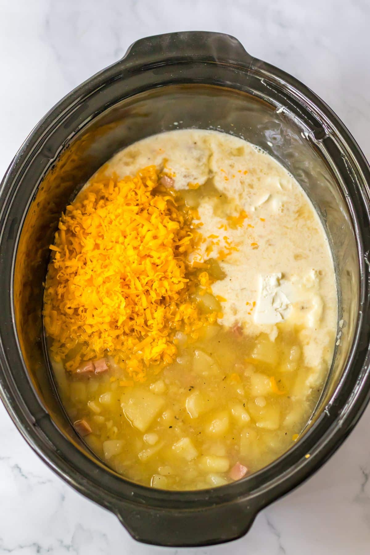 cheese and milk being added to potatoes in a slow cooker.