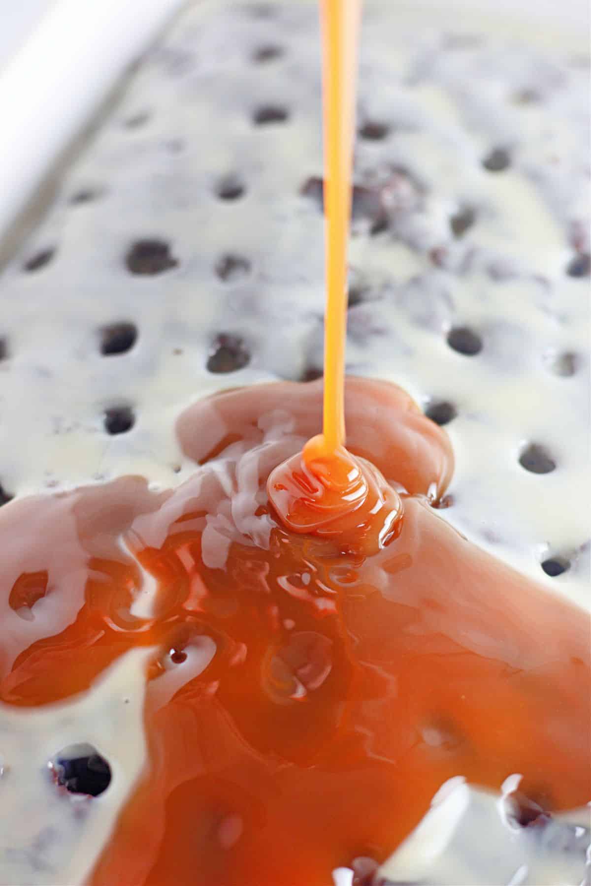 condensed milk and caramel sauce being poured on top of poke cake.