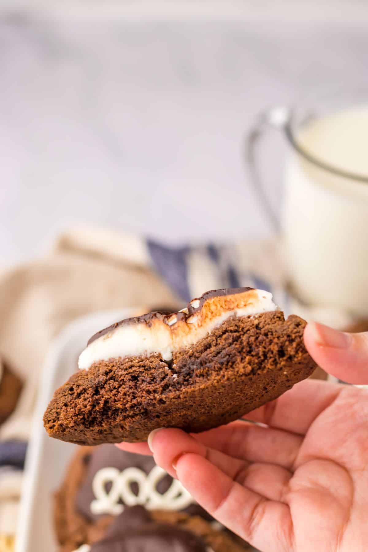hostess cupcake cookie split in half and held in the air in a woman's hand.