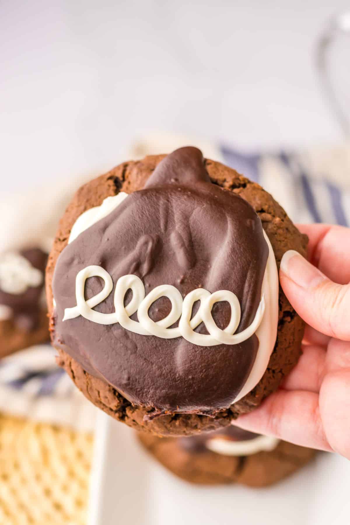 hostess cupcake cookie held in the air in a woman's hand.