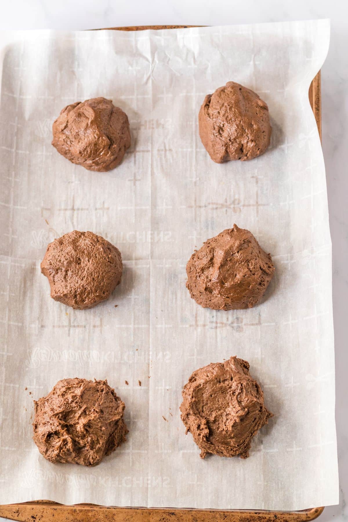chocolate cookie dough balls on a baking sheet.