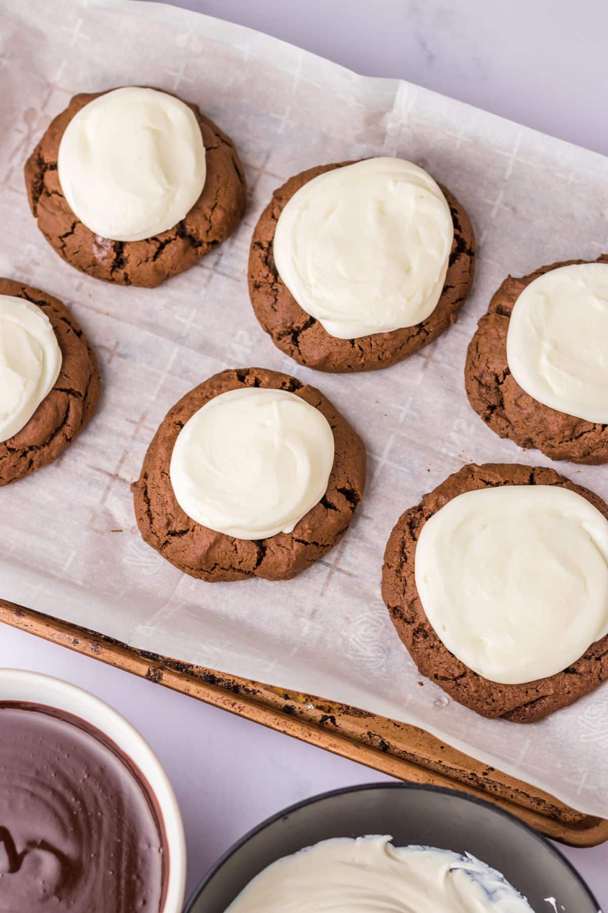 buttercream frosting being added on top of cookies.