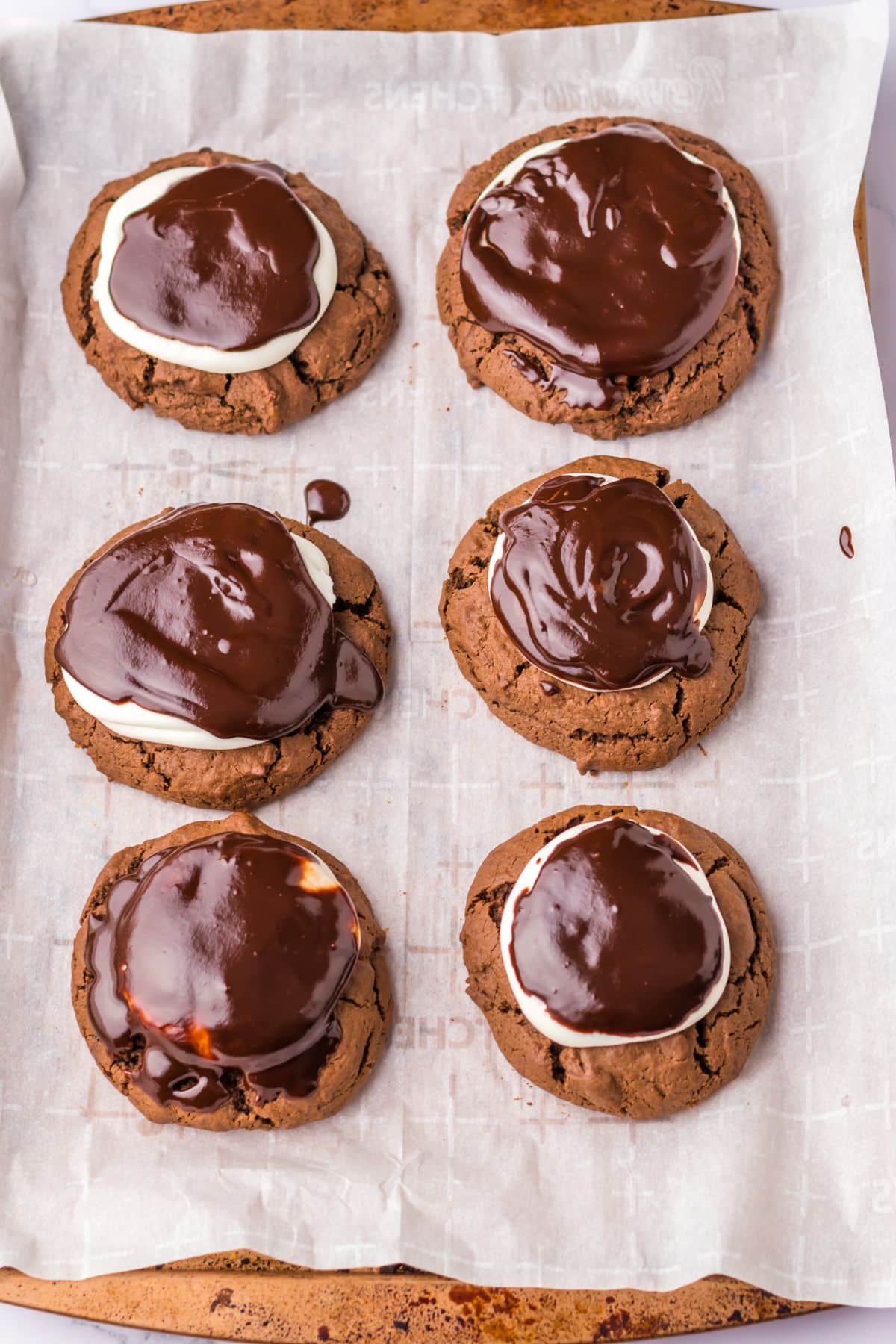 chocolate ganache being added on top of cookies.