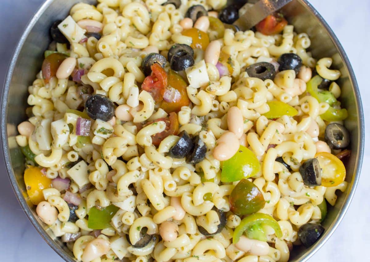 italian pasta salad chilling in a stainless steel mixing bowl.