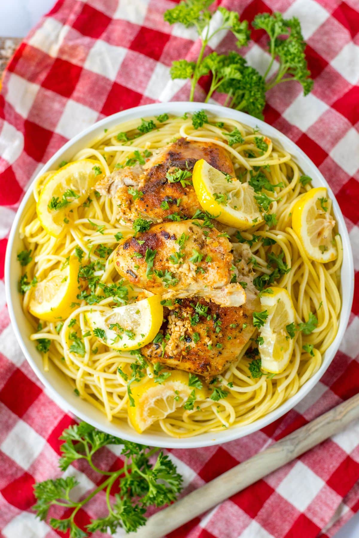 bowl full of spaghetti noodles and topped with slow cooker lemon chicken thighs.
