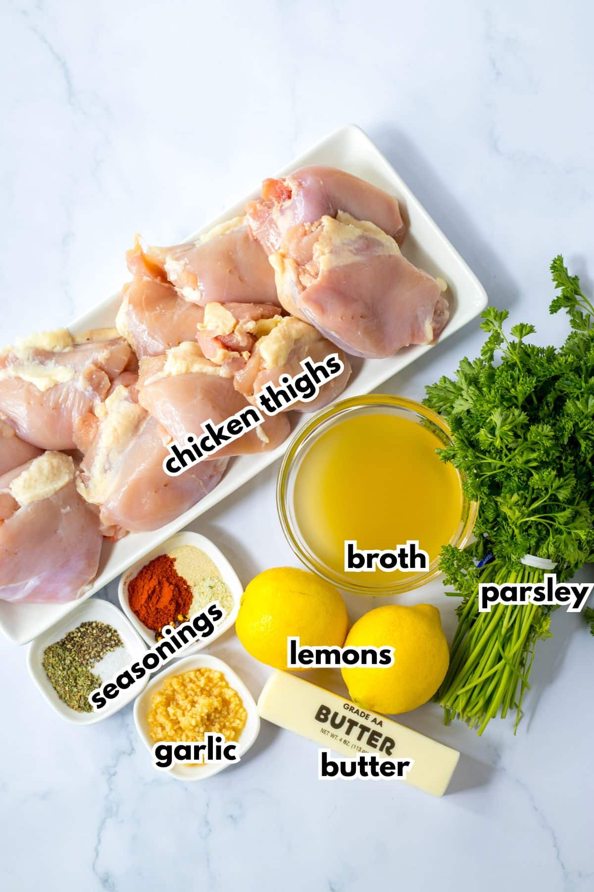 bowls of chicken thighs, seasonings, garlic, lemons, broth, butter, and parsley.