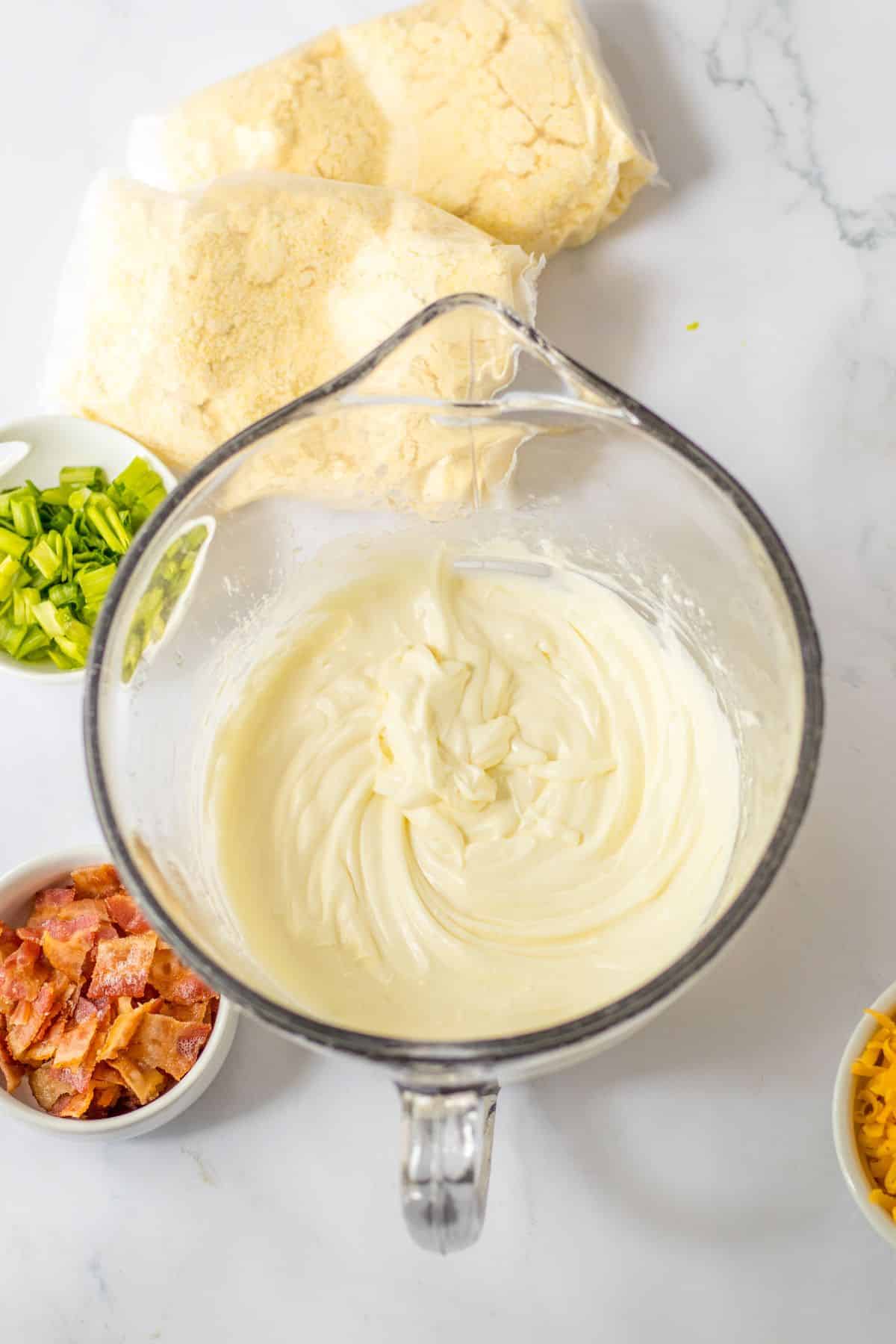 cream cheese and butter being melted in a glass mixing bowl.
