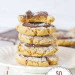 five muddy buddy cookies stacked on a plate the top one has a bite missing.