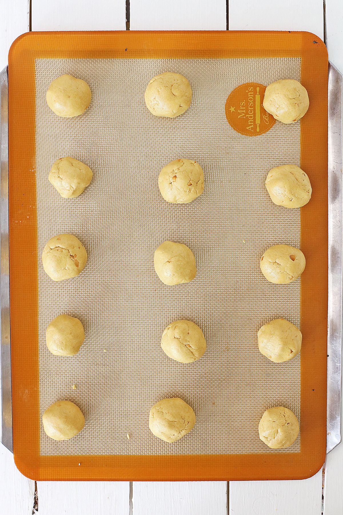 raw peanut butter cookie dough balls on a silicone mat lined baking sheet.