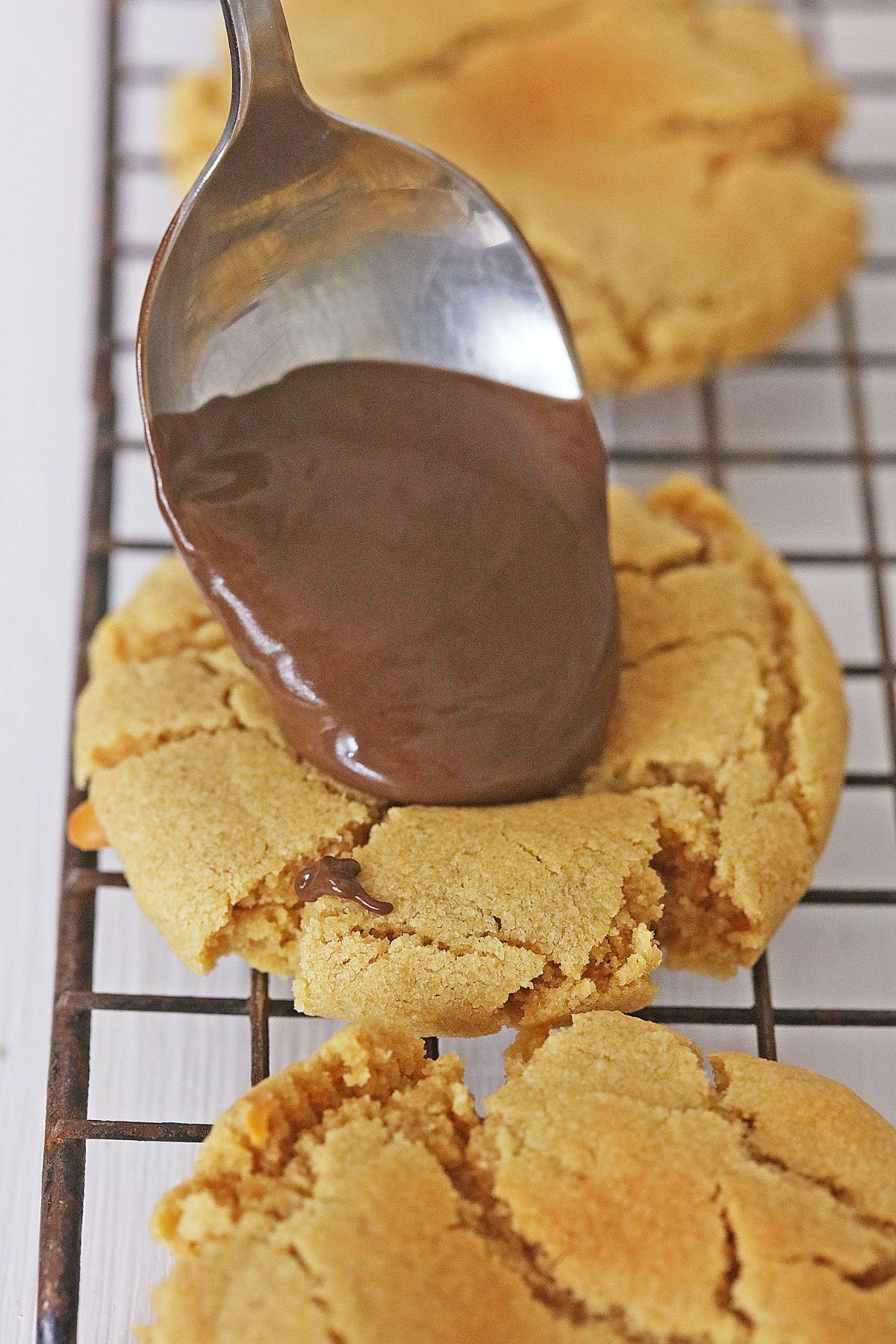 chocolate ganache being added to the top of peanut butter cookies.