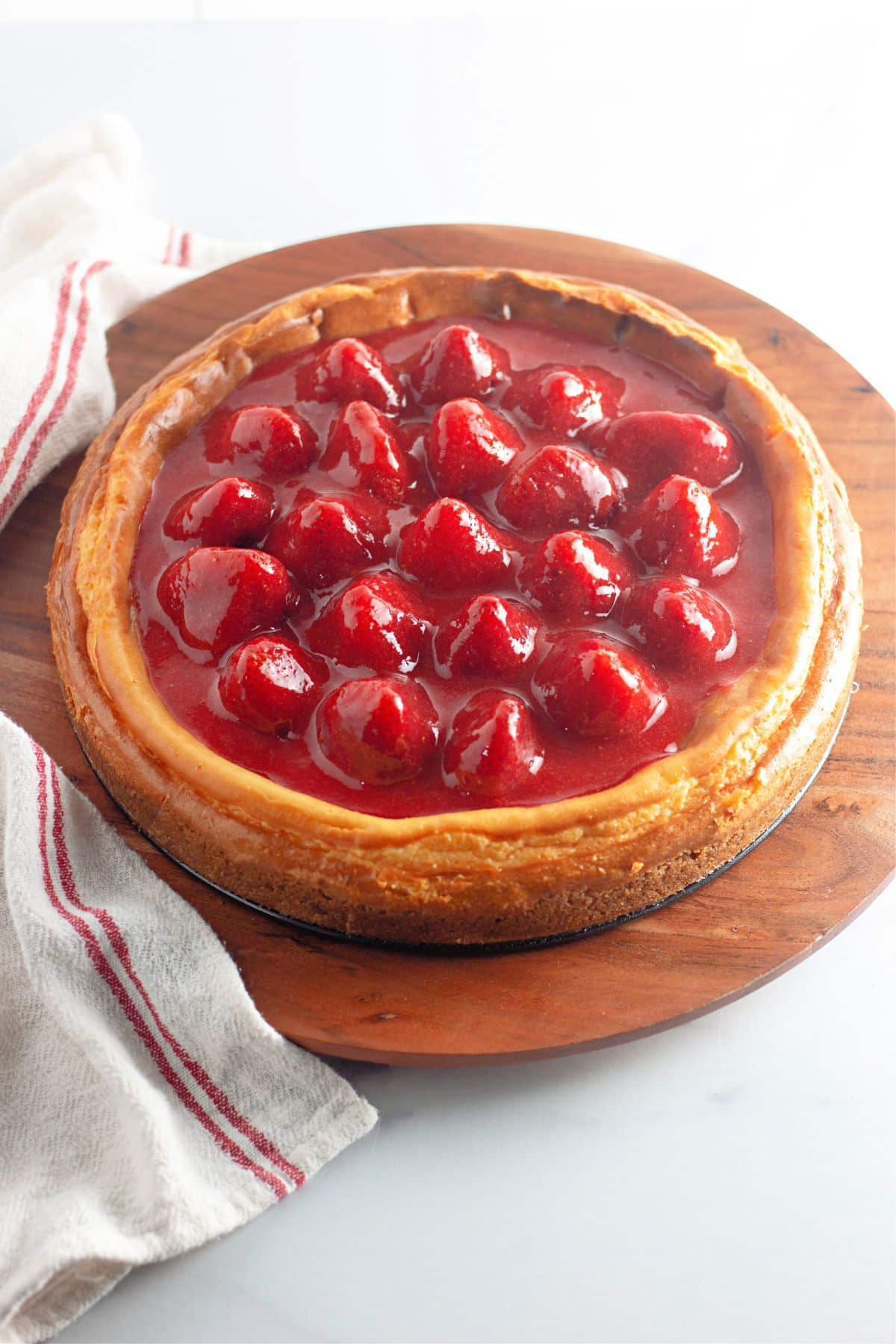 uncut new york cheesecake on a wooden cutting board.
