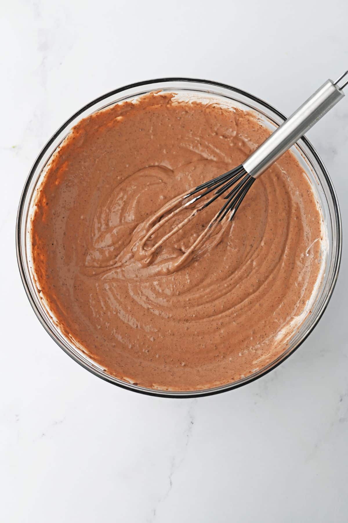 chocolate pudding and whipped topping being mixed together in a glass bowl.