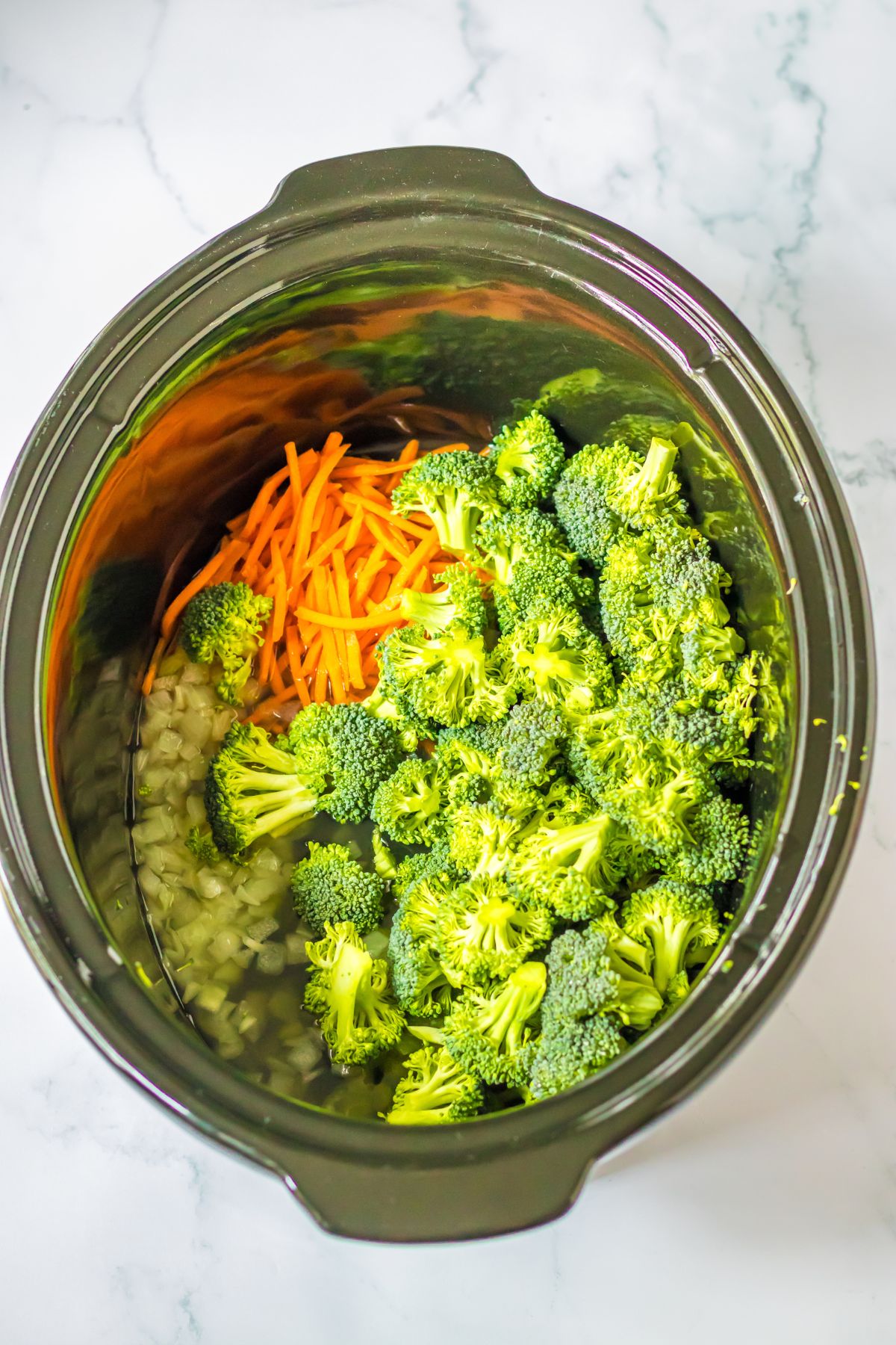raw broccoli, carrots, celery, and onions in a slow cooker.
