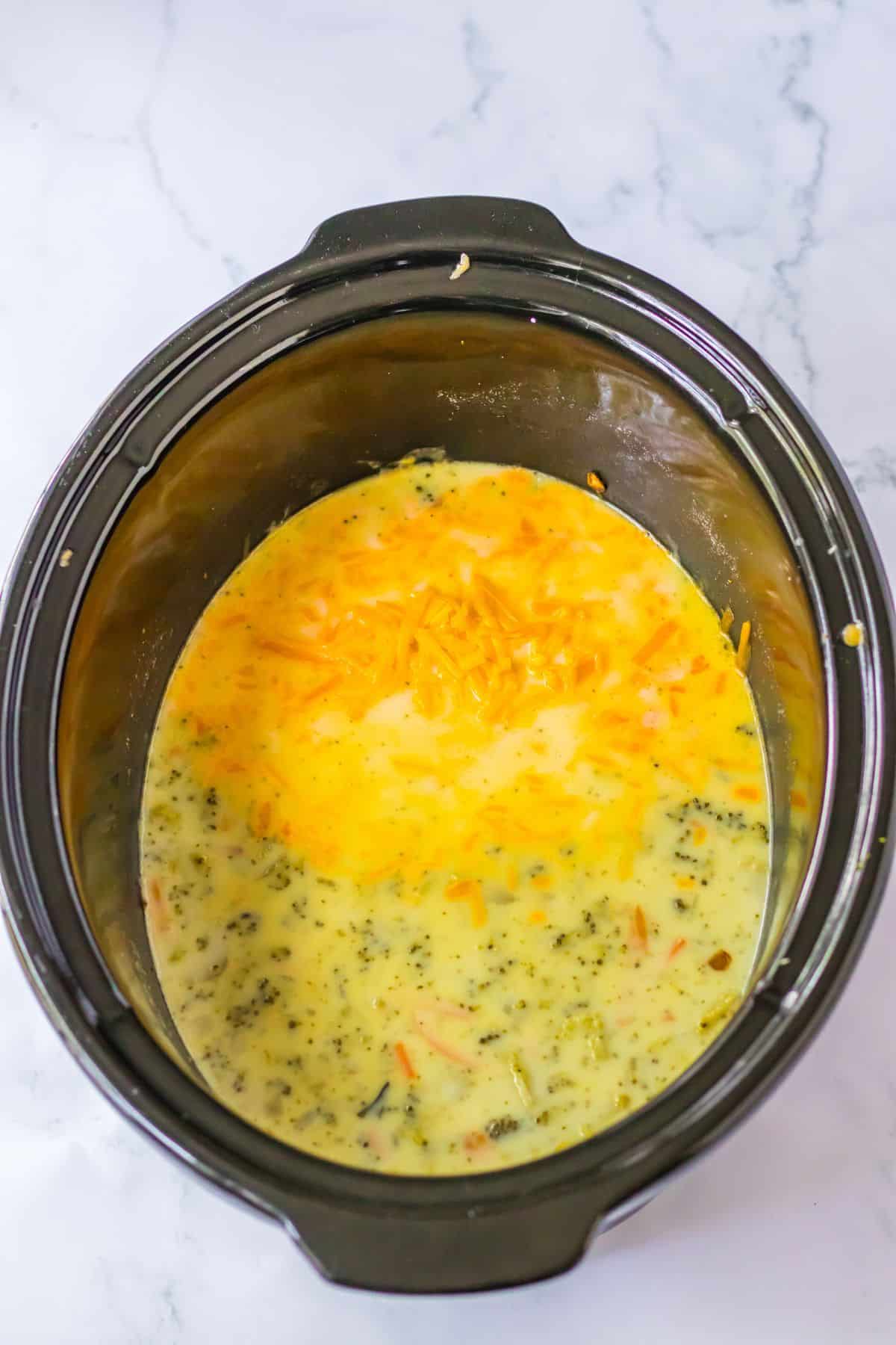 cheese and roux added to a slow cooker full of broccoli soup.