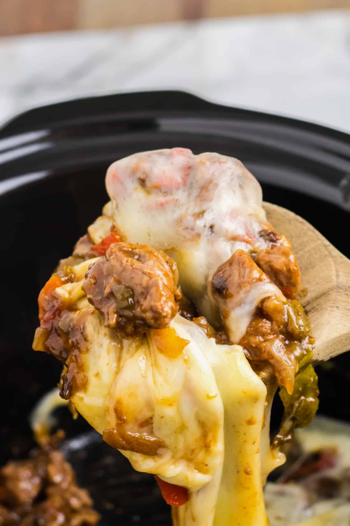 wooden spoon of philly cheesesteak bites held in the air.