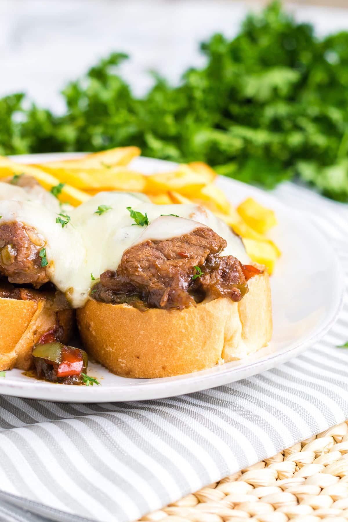 slow cooker philly cheesesteak bites on top of bread slices on a plate.