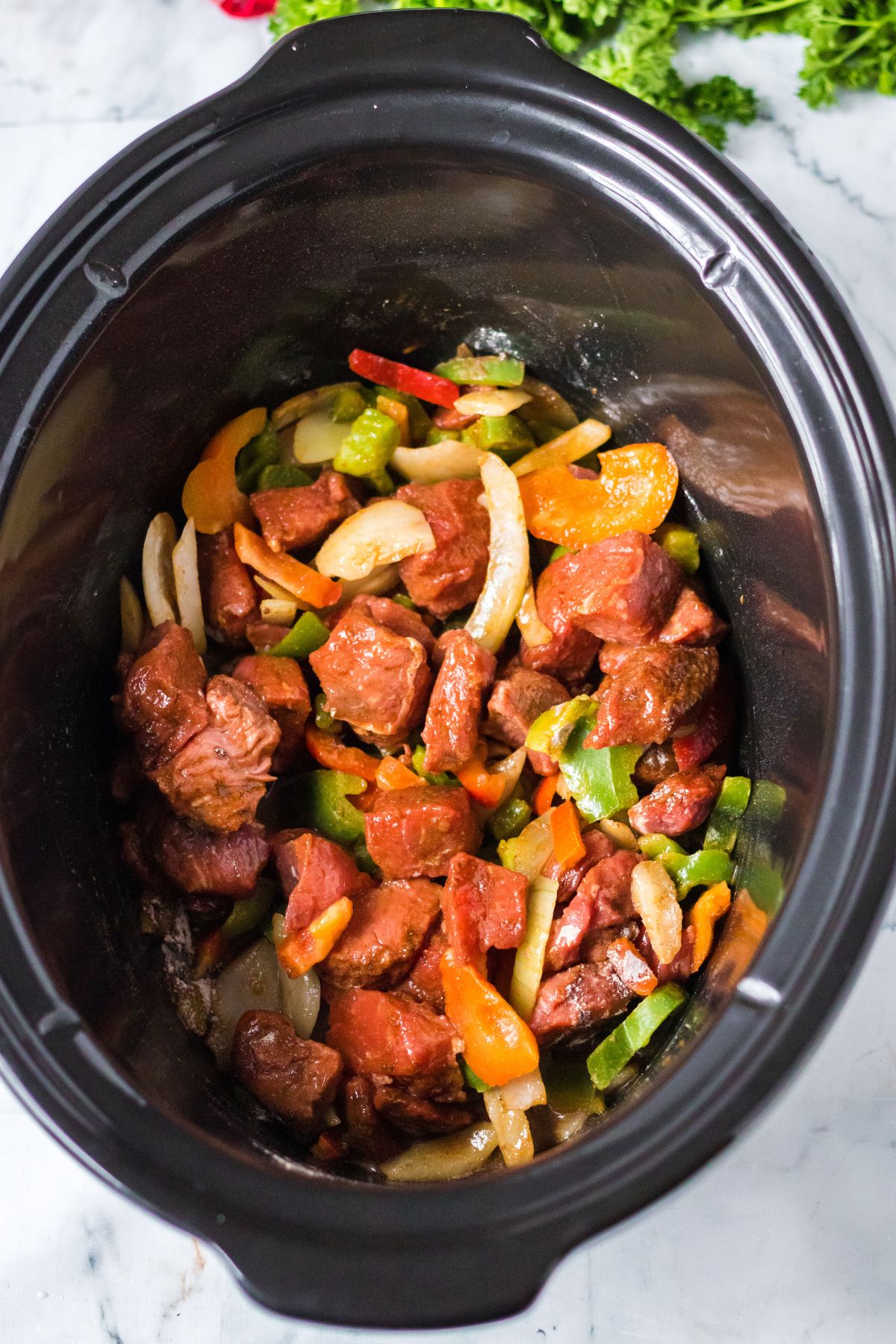 raw beef and peppers in a slow cooker.