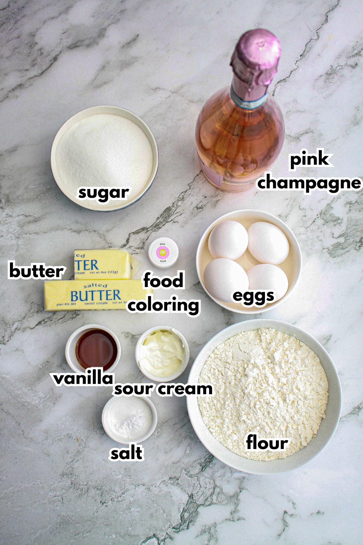 bowls of sugar, butter, food coloring, vanilla, sour cream, salt, flour, eggs and pink champagne.