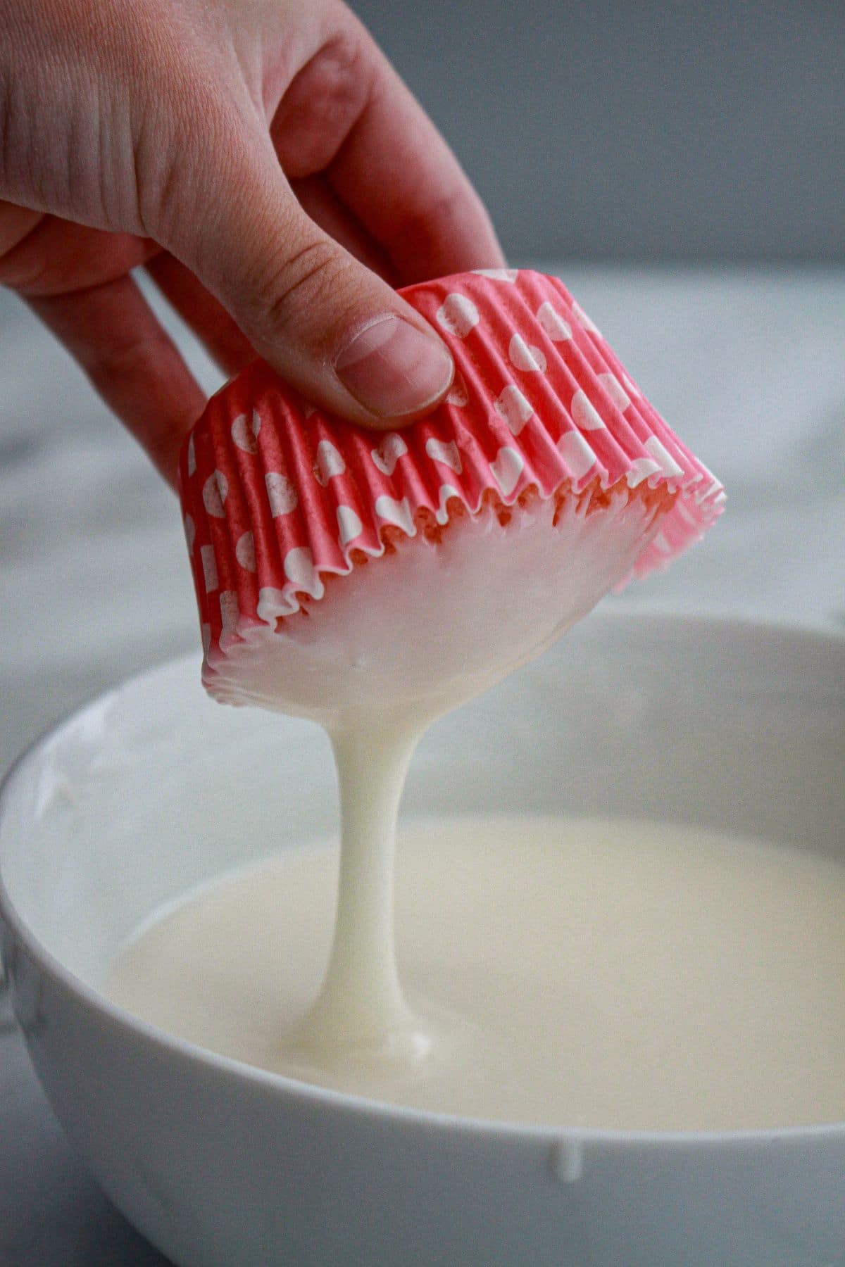cupcake being dipped into glaze upside down.