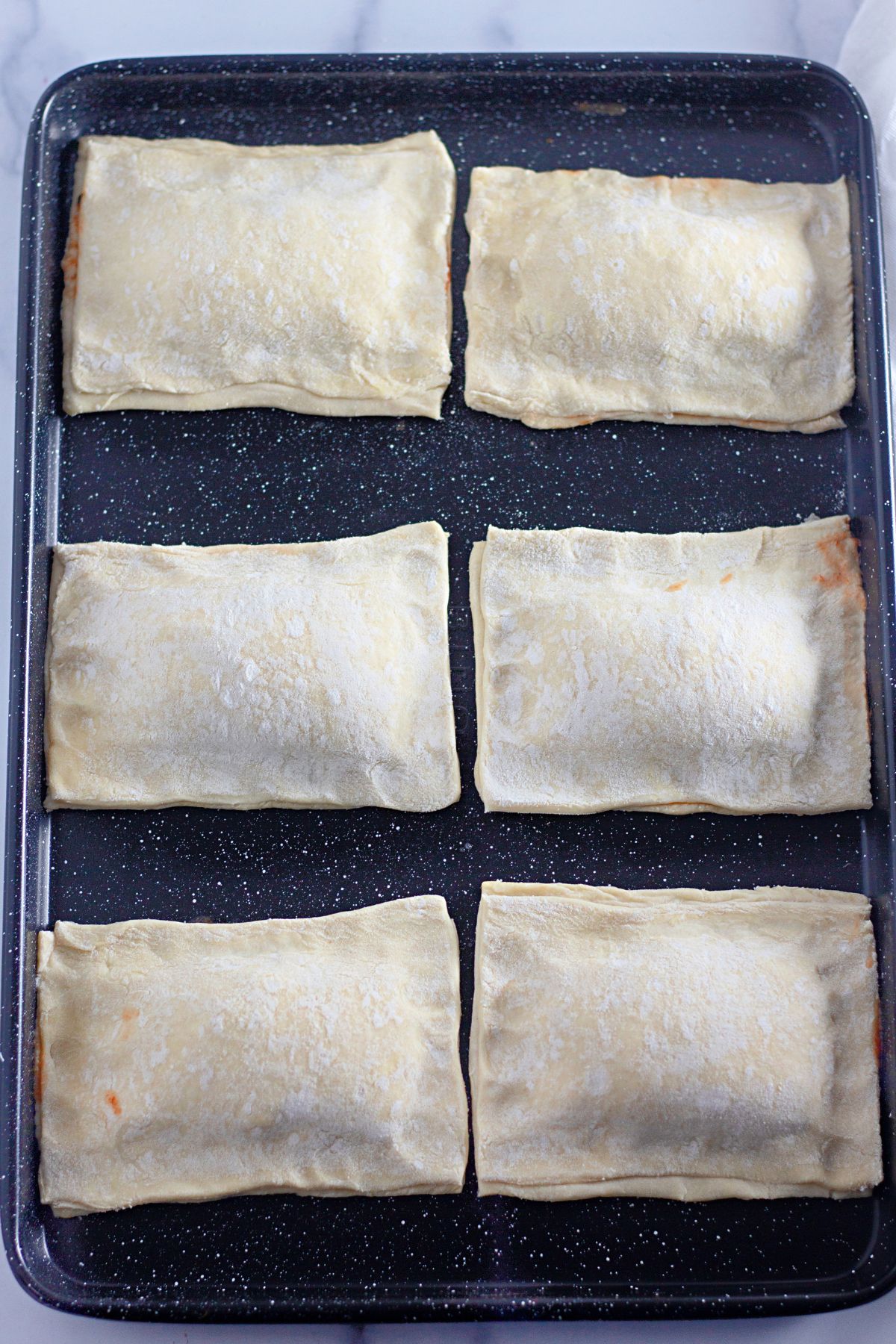 pizza pockets being sealed shut on a baking sheet.