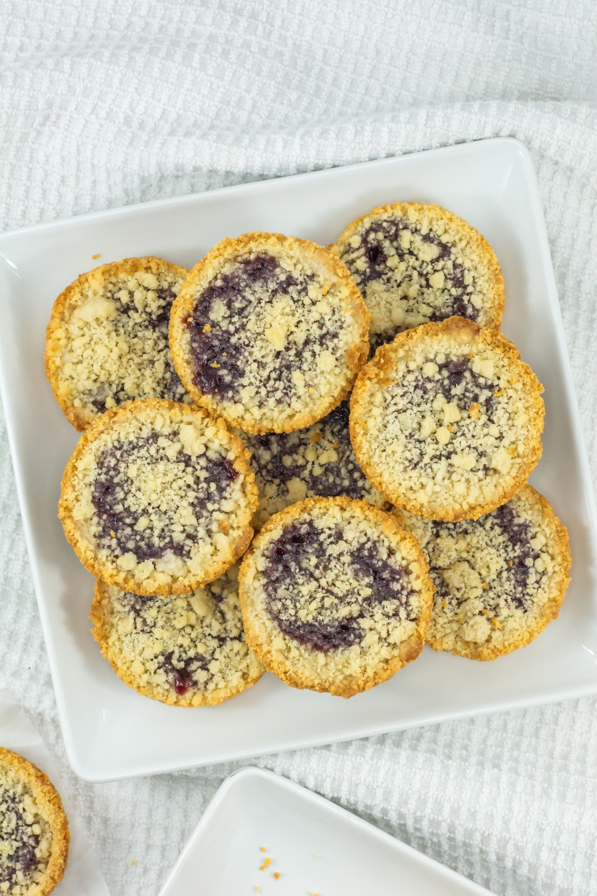 raspberry crumble cookies stacked in a pyramid on a plate.