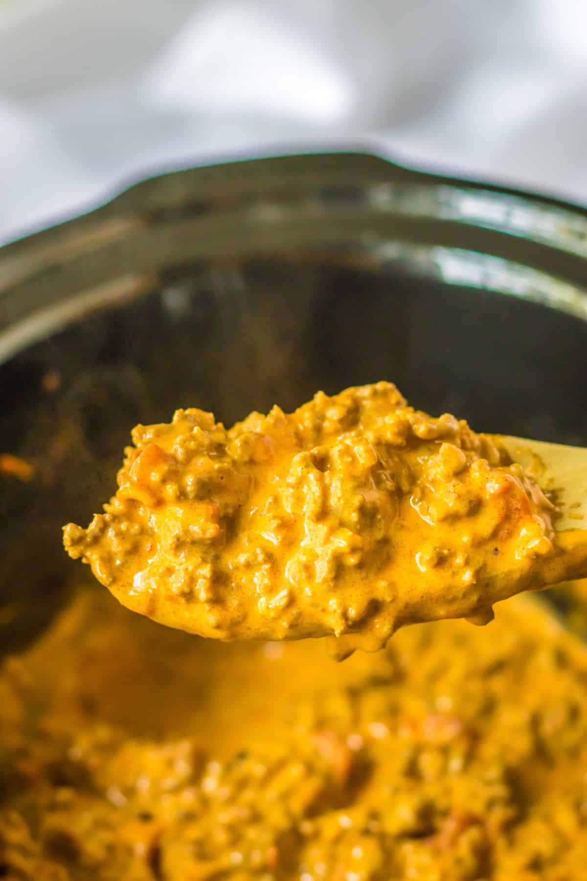 spoonful of cheesy rotel ground beef in a slow cooker.