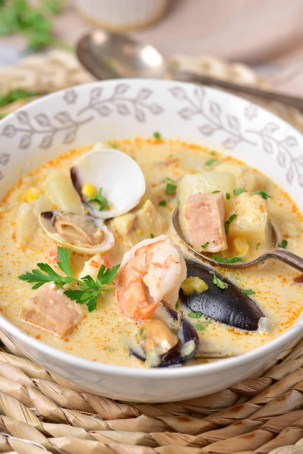 bowl full of seafood chowder on a bamboo place mat.