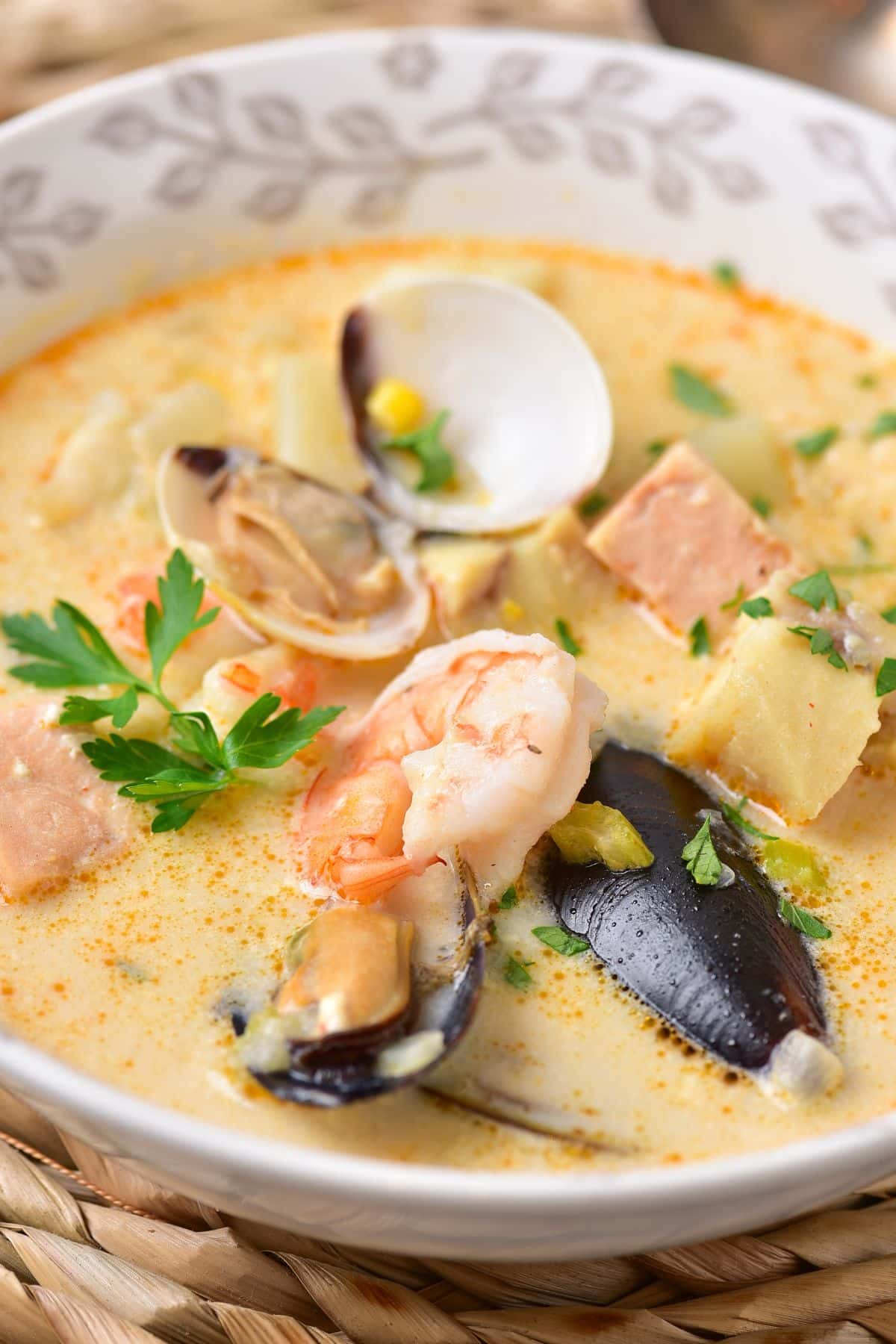 bowl full of seafood chowder on a bamboo place mat.