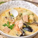 bowl full of seafood chowder on a bamboo place mat.