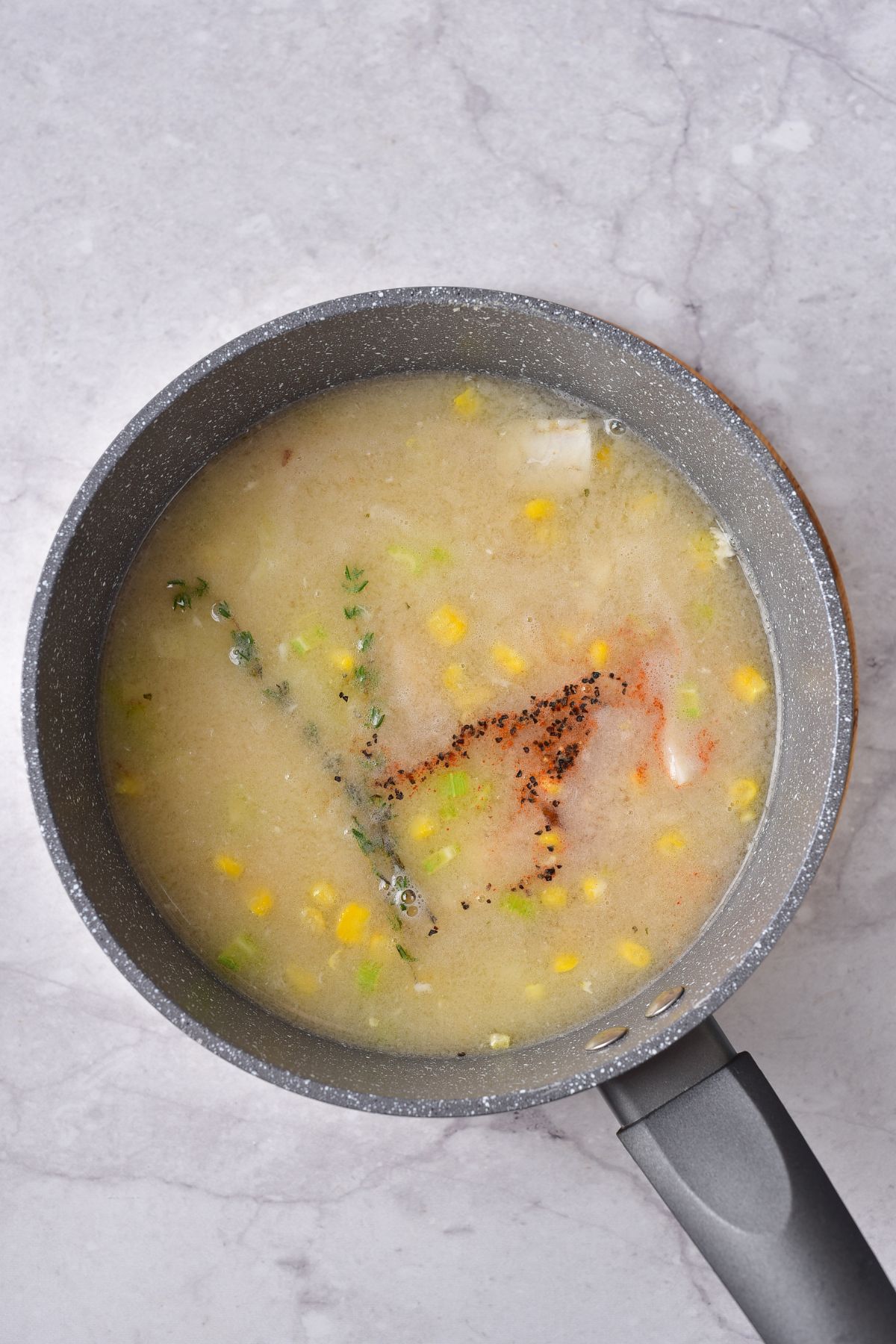 corn, seasonings and broth being added to a large pot.