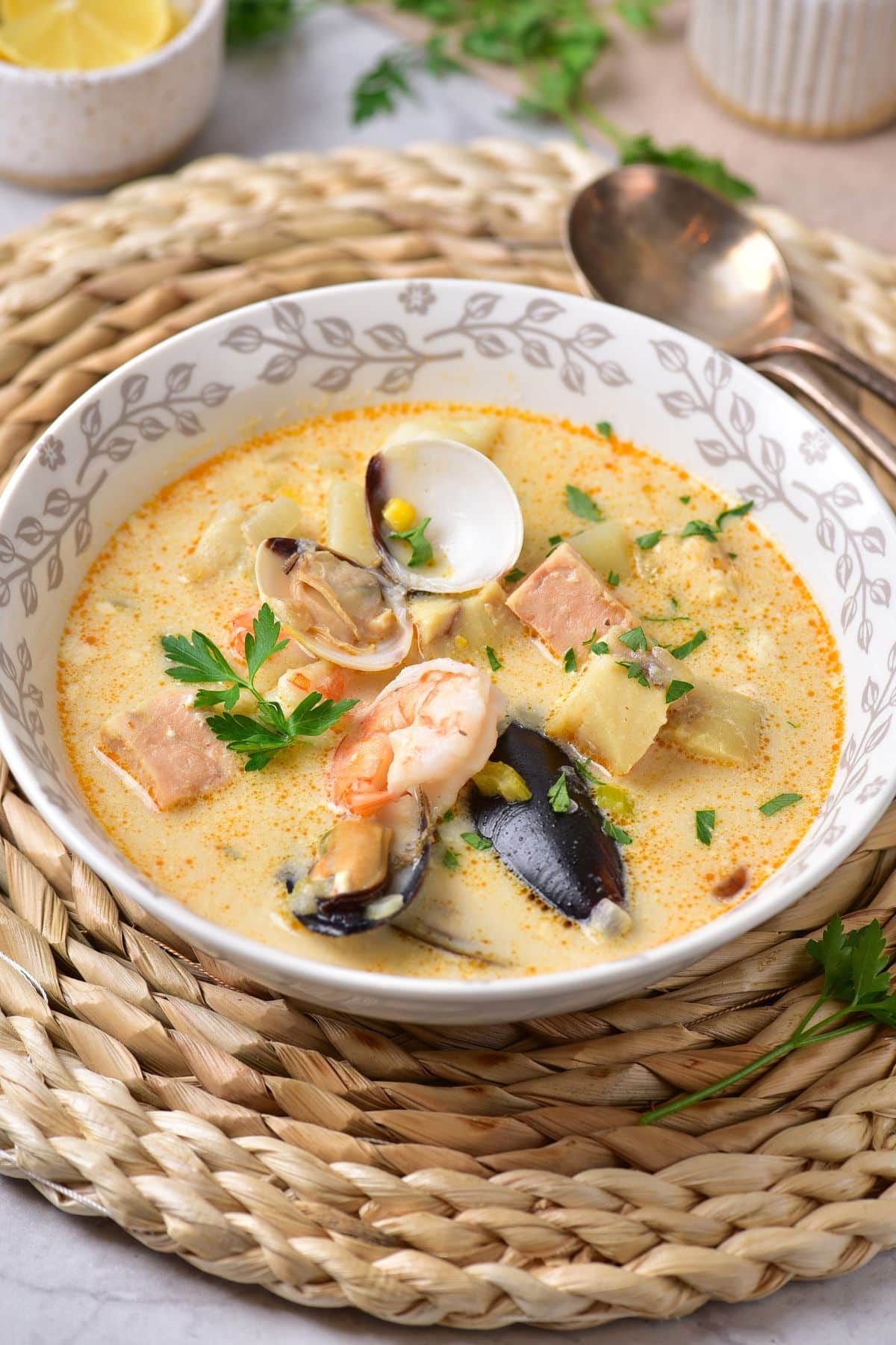 bowl full of seafood chowder on a bamboo place mat.
