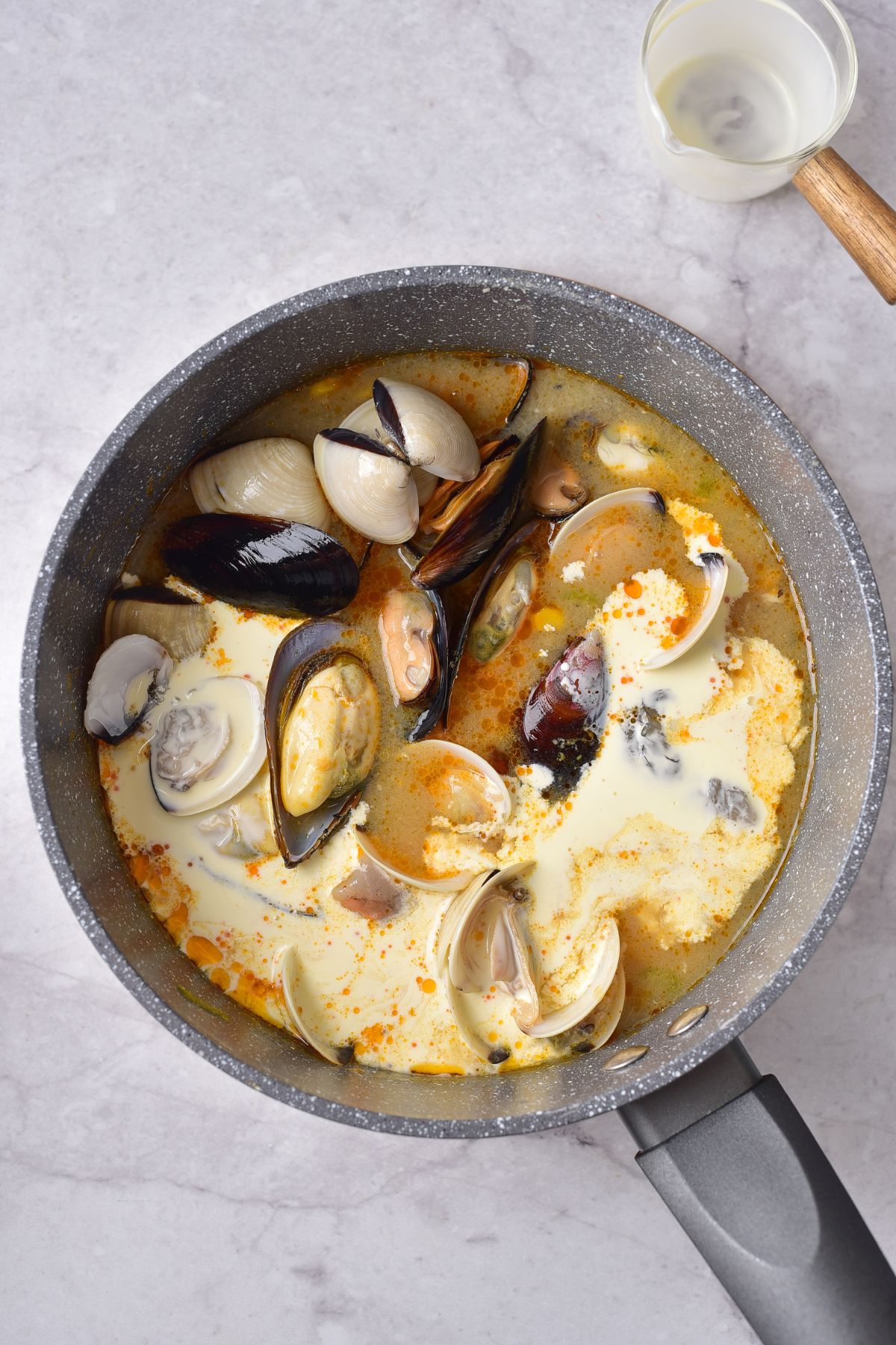 clams and shrimp being added to seafood chowder.