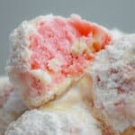 stack of strawberry snowball cookies with the top cookie bitten in half.