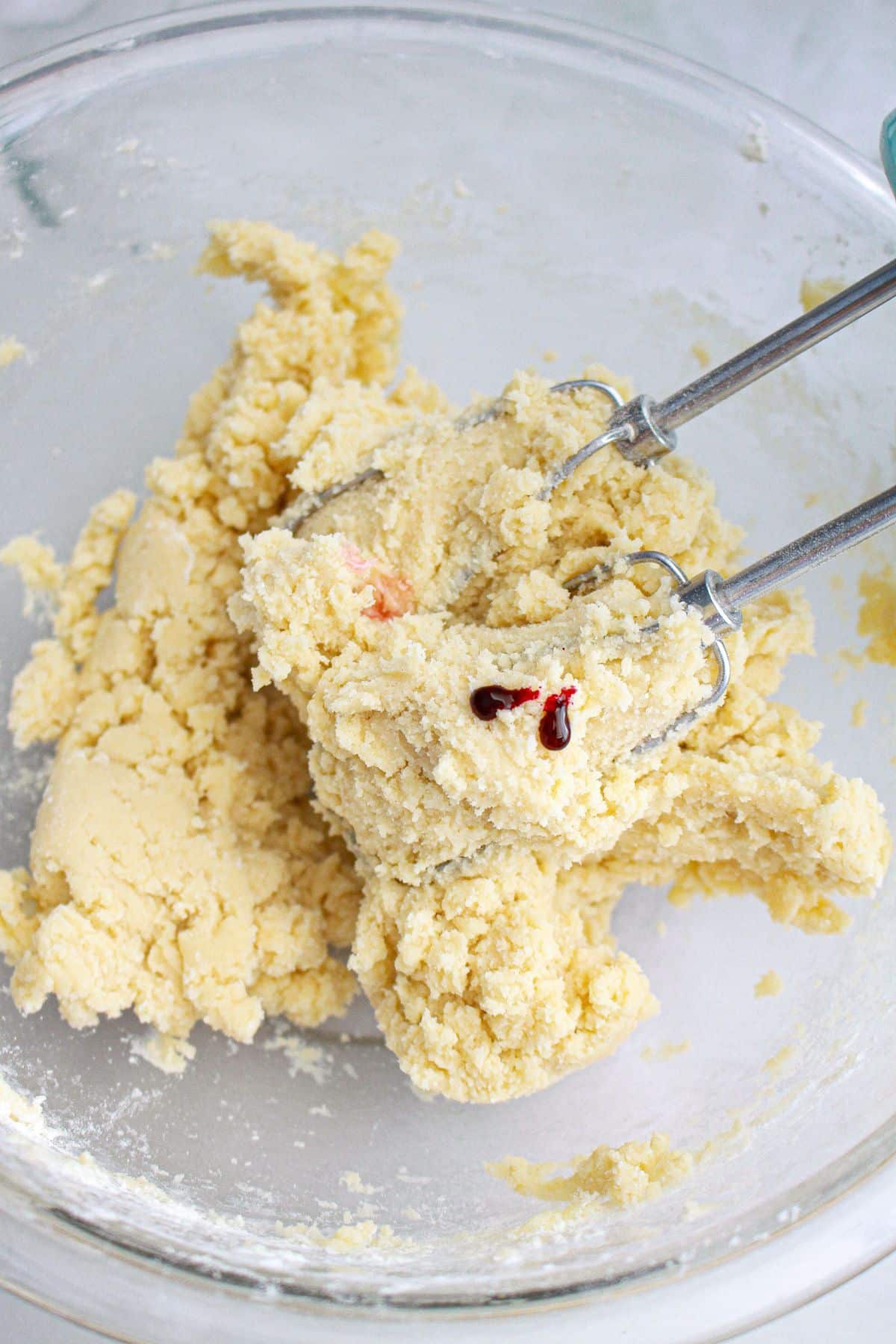 cookie dough being mixed in a glass mixing bowl.