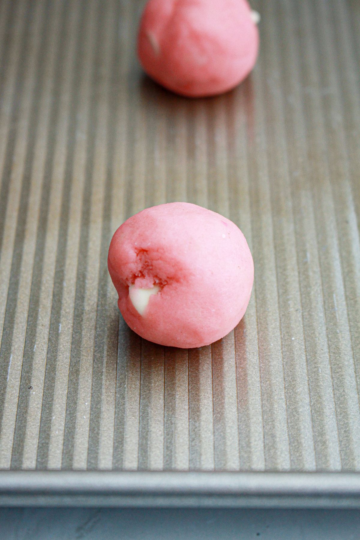 strawberry cookie dough ball on a baking sheet ready for the oven.