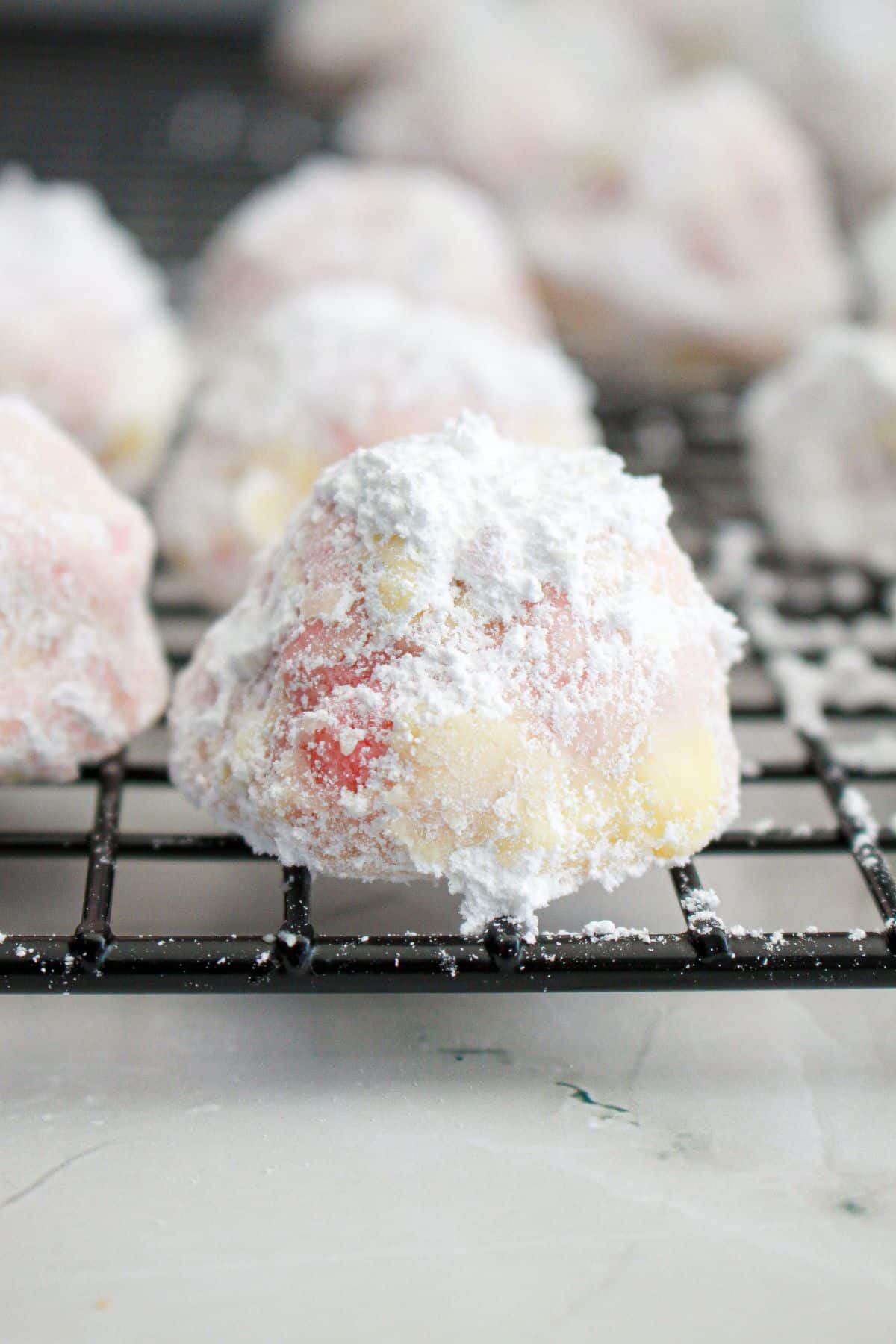 strawberry snowball cookie cooling on a wire rack.