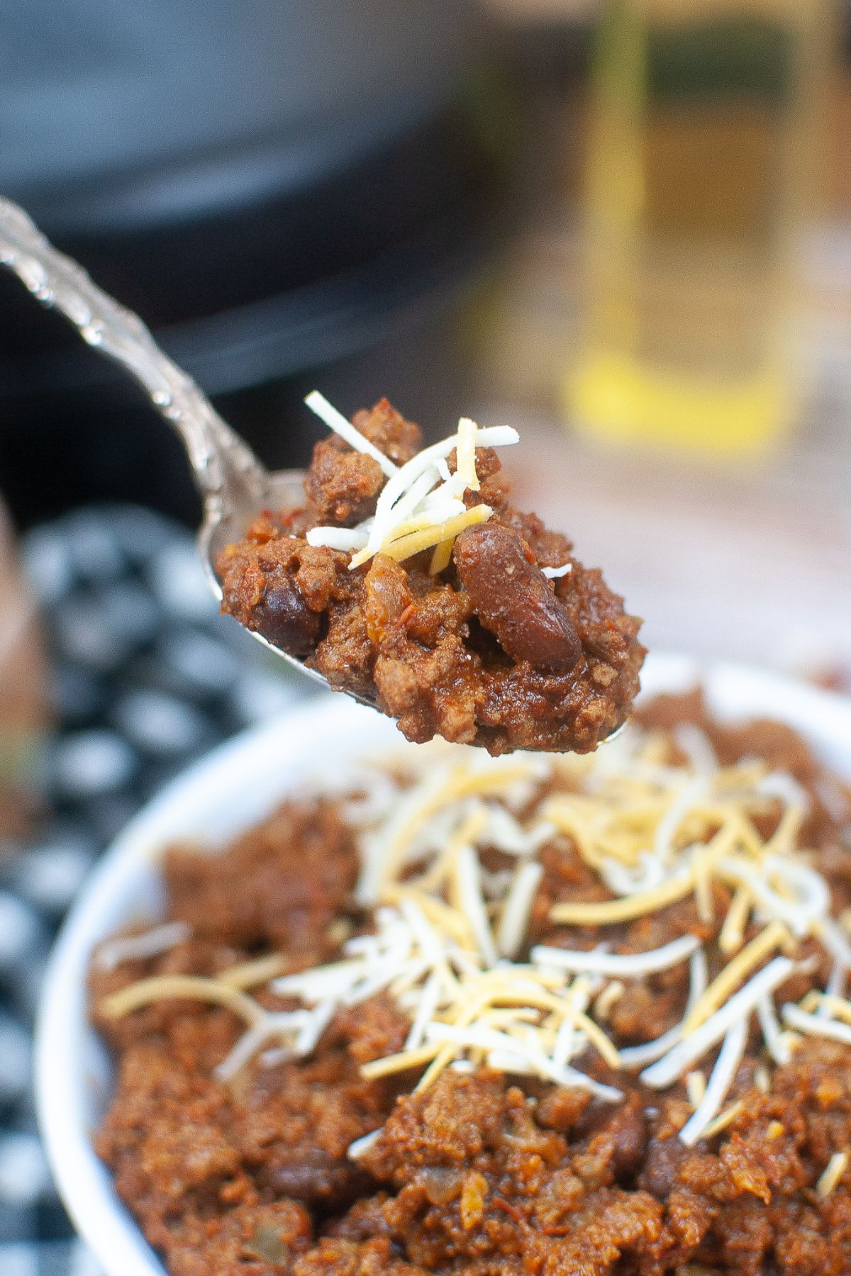 spoonful of texas roadhouse chili held in the air above a bowl.