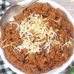 bowl full of texas roadhouse chili topped with a sprinkle of grated cheese.