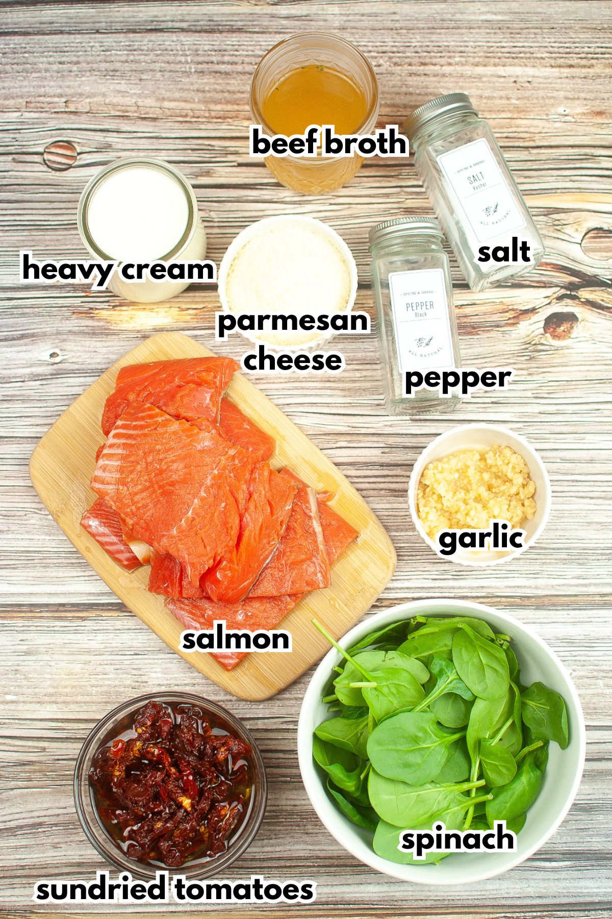 bowls of heavy cream, parmesan cheese, pepper, salt, salmon, garlic, sundried tomatoes, and baby spinach.