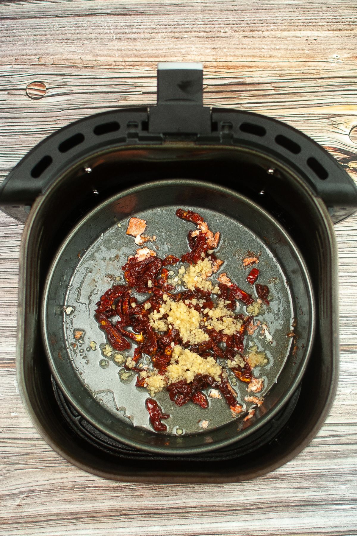 garlic and sundried tomatoes in a cake mix in an air fryer basket.