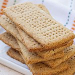 whole wheat graham crackers stacked on a white plate.