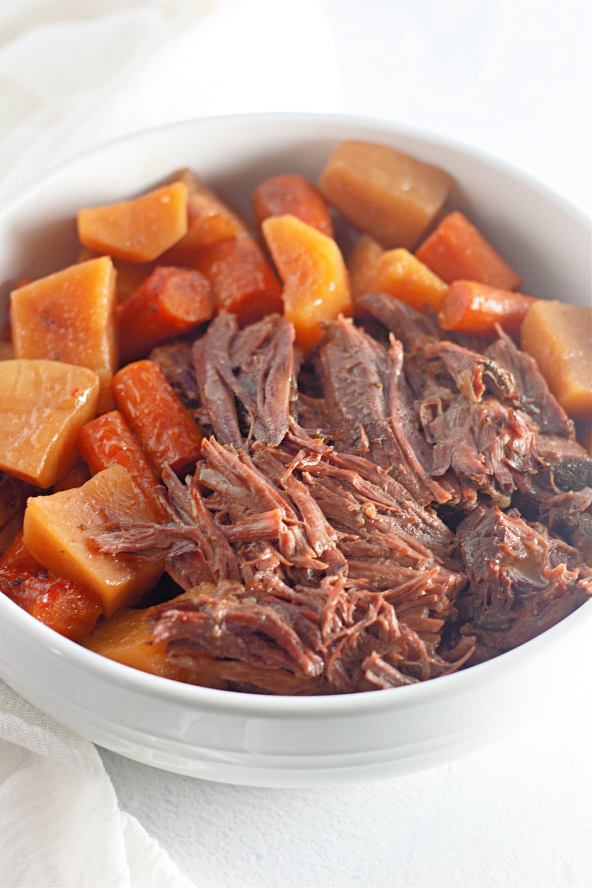 bowl full of pot roast, potatoes and carrots on a counter.