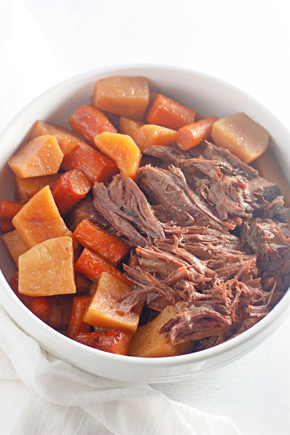 bowl full of pot roast, potatoes and carrots on a counter.