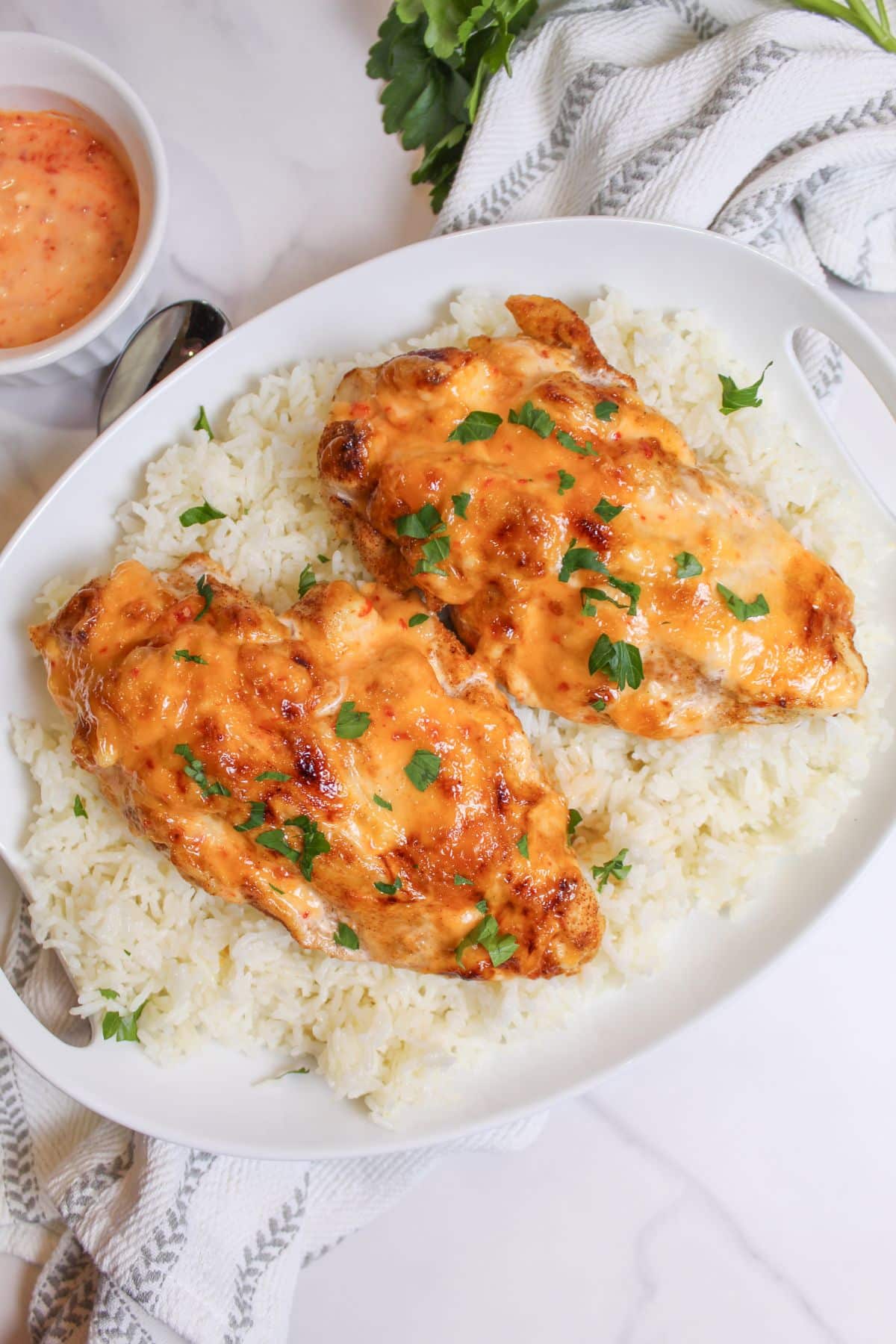 air fryer bang bang chicken on top of a bed of white rice on a plate.