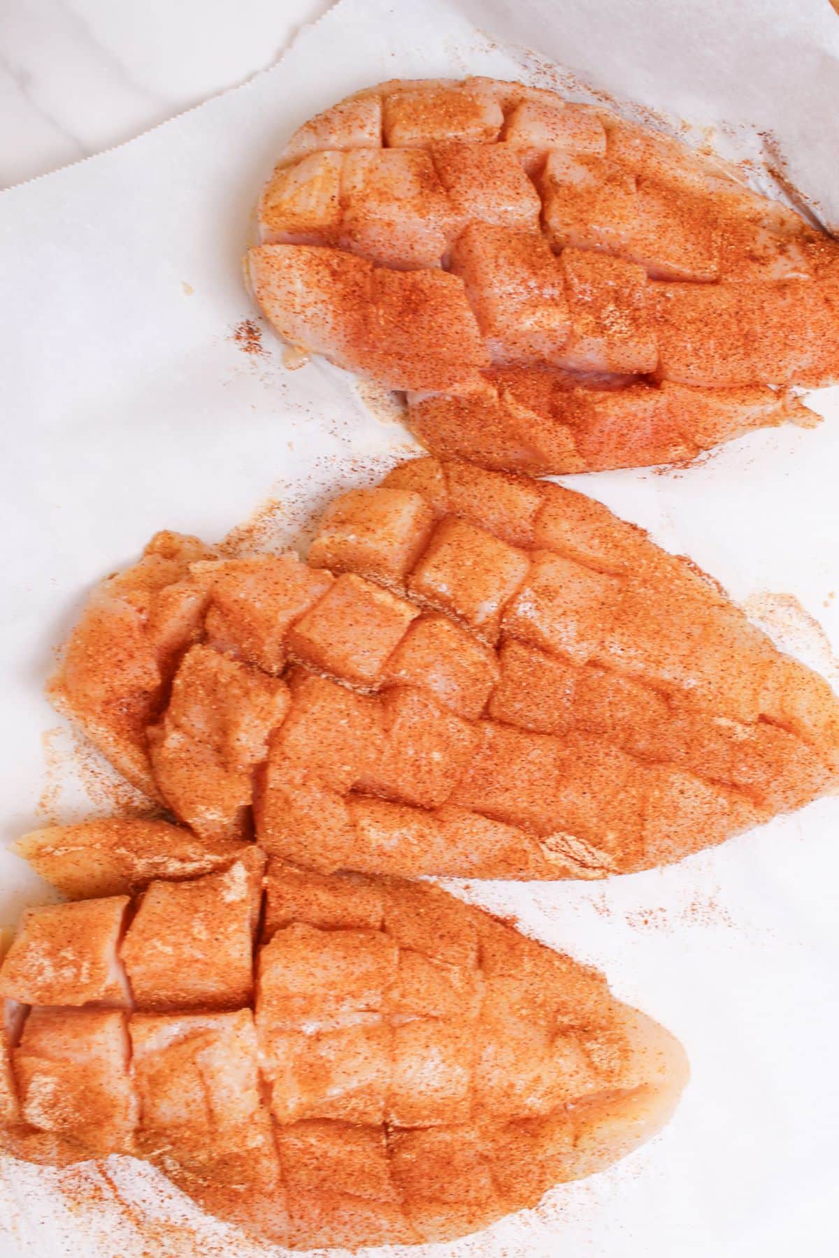 chicken breasts being cut and seasoned.